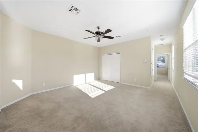 an empty room with windows and fan