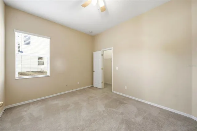 an empty room with ceiling fan and window