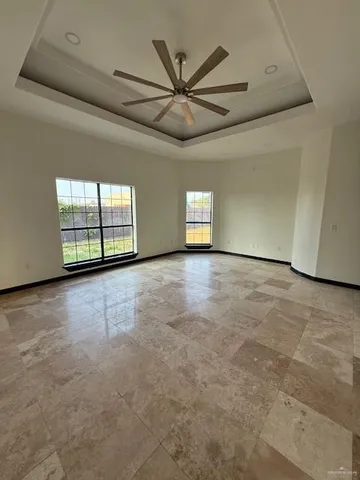 an empty room with windows and ceiling fan