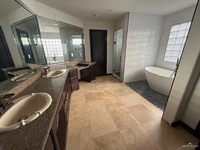 a bathroom with a granite countertop sink a toilet a mirror and tub