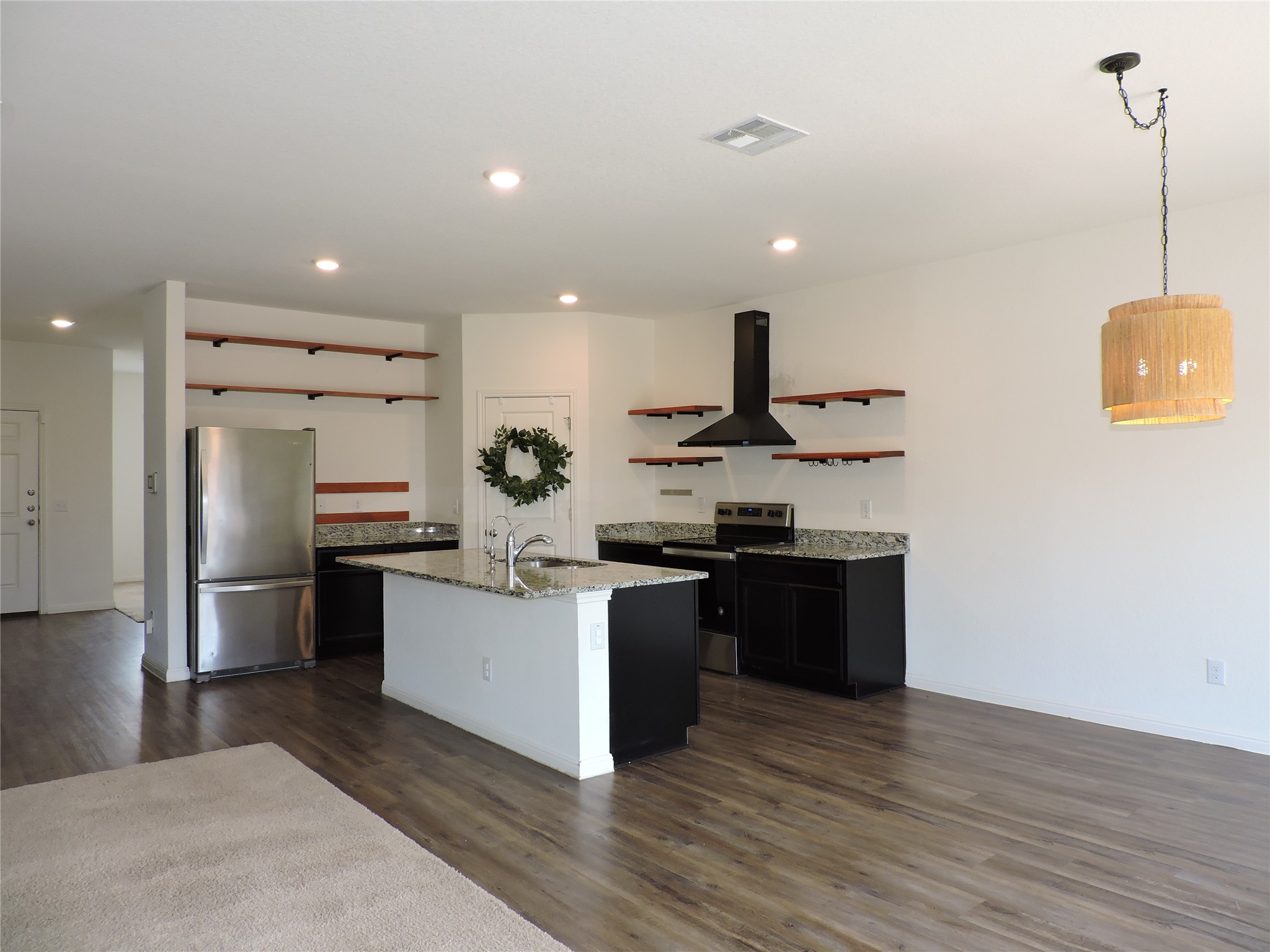 14120 Jeannette Rankin Rd Manor Manor, TX 78653 - Photo 4 of 25 Kitchen featuring light stone counters, stainless steel appliances, open shelves, dark cabinets, and dark wood-type flooring