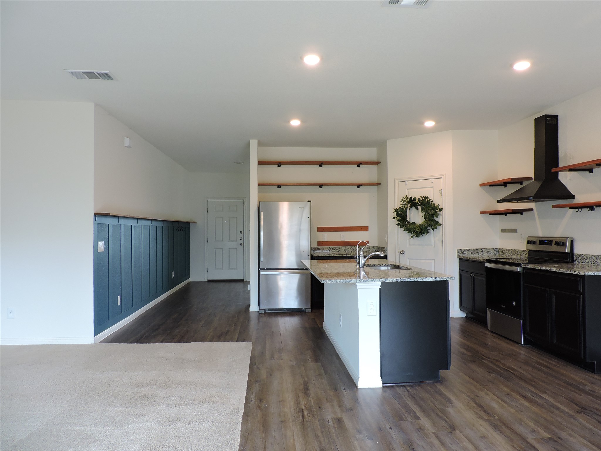 14120 Jeannette Rankin Rd Manor Manor, TX 78653 - Photo 5 of 25 Kitchen featuring stainless steel appliances, light stone counters, ventilation hood, open shelves, and dark wood-style flooring