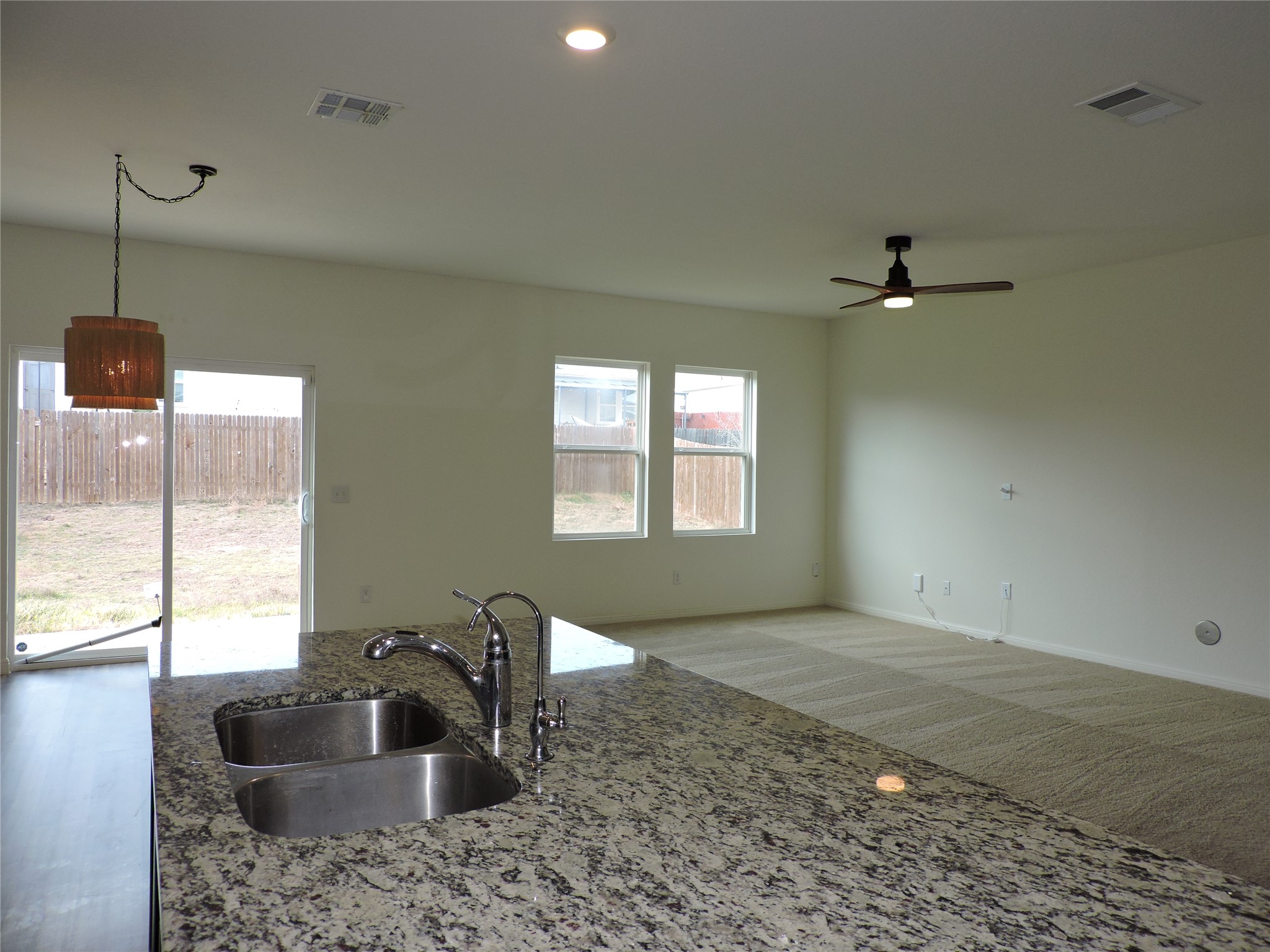 14120 Jeannette Rankin Rd Manor Manor, TX 78653 - Photo 6 of 25 Kitchen featuring light stone countertops, carpet, hanging light fixtures, a ceiling fan, and healthy amount of natural light