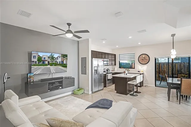 a living room with furniture a flat screen tv and kitchen view