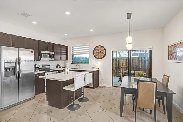 a kitchen with stainless steel appliances kitchen island granite countertop a sink a stove a refrigerator and island