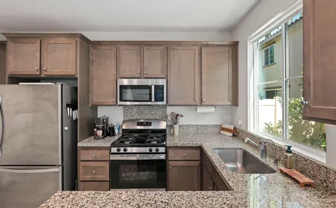 a kitchen with granite countertop a refrigerator stove and microwave