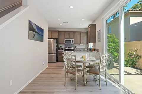 a kitchen with stainless steel appliances a dining table chairs and granite counter tops