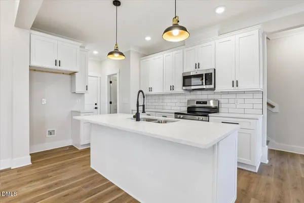 a kitchen with stainless steel appliances a stove a sink and white cabinets