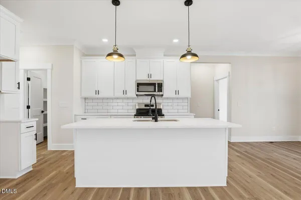 a kitchen with stainless steel appliances granite countertop a sink a refrigerator a stove and white cabinets with wooden floor