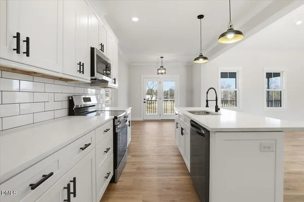 a kitchen with stainless steel appliances a sink a stove and a wooden floors