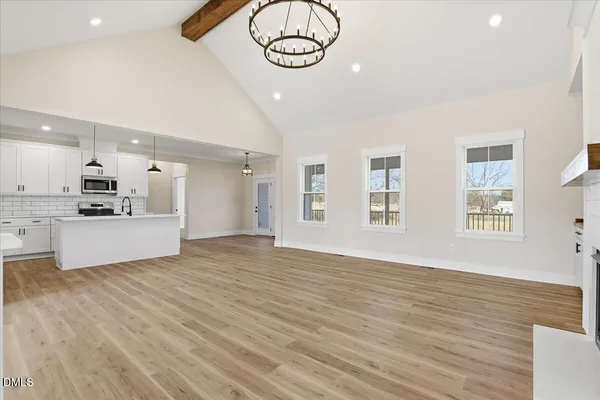 a view of kitchen and empty room with wooden floor