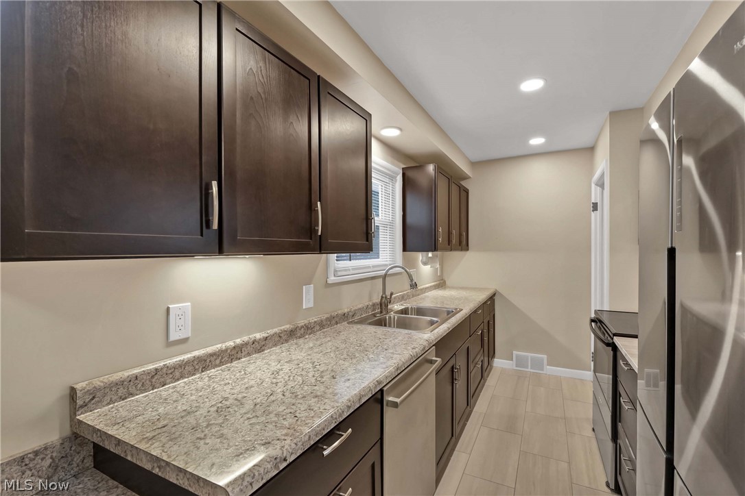 7528 State Road Parma, OH 44129 - Photo 13 of 40 Kitchen featuring appliances with stainless steel finishes, dark brown cabinets, and sink