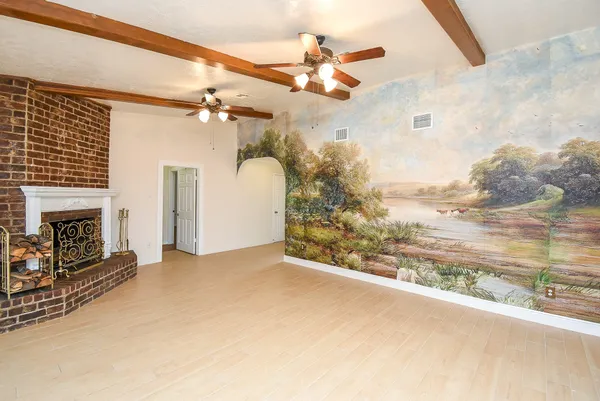 an empty room with wooden floor and fan