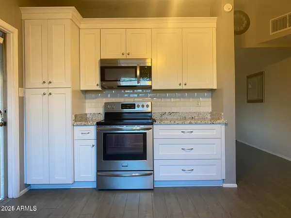 a kitchen with stainless steel appliances granite countertop white cabinets and a stove