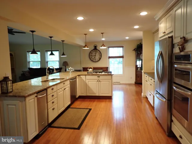 a kitchen with stainless steel appliances a sink cabinets and wooden floor
