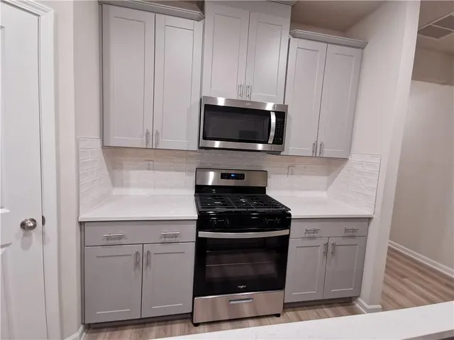 a kitchen with white cabinets and black appliances