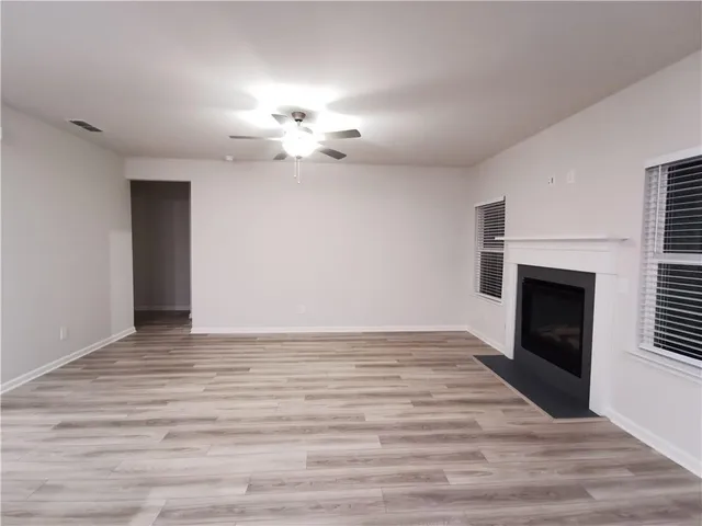 a view of empty room with wooden floor and fireplace