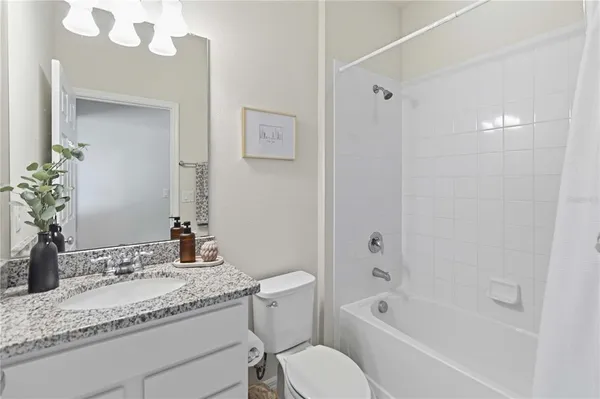 a bathroom with a granite countertop sink mirror toilet and bathtub