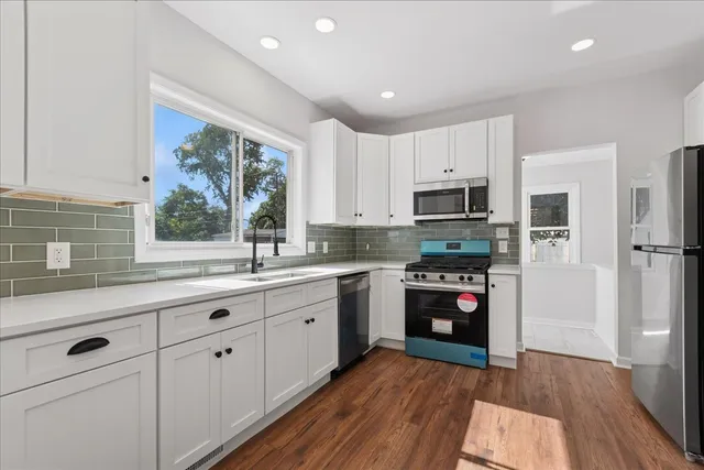 a kitchen with granite countertop white cabinets and stainless steel appliances