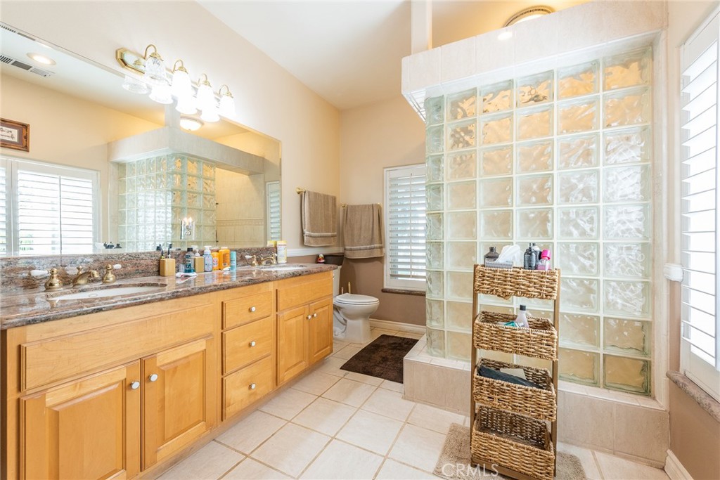 1413 Irving Street Riverside, CA 92504 - Photo 13 of 29 a bathroom with a double vanity sink a toilet a mirror and shower