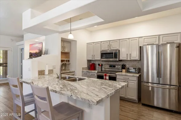 a kitchen with stainless steel appliances granite countertop a stove refrigerator and microwave