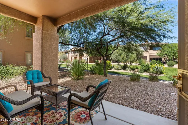 a view of a backyard with table and chairs potted plants and large tree