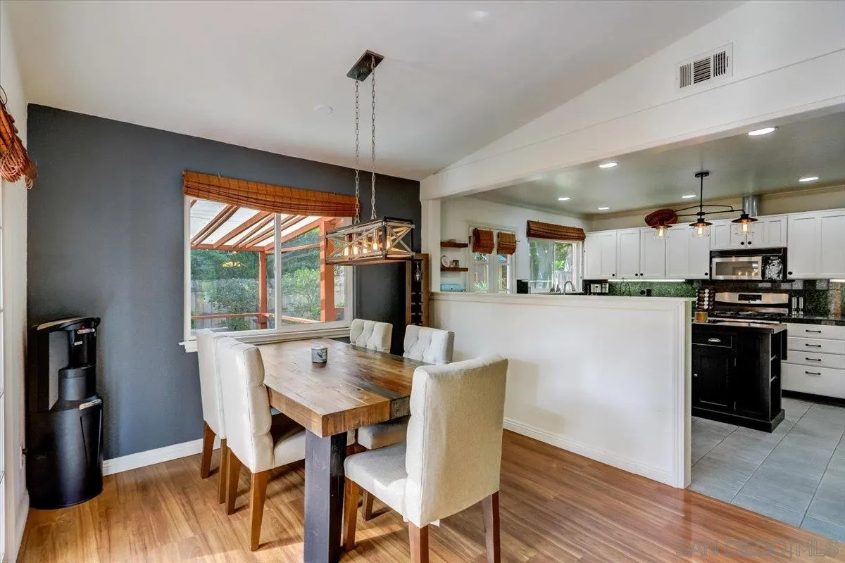 861 Shade Tree Lane Fallbrook, CA 92028 - Photo 8 of 49 a kitchen with stainless steel appliances kitchen island granite countertop a dining table chairs and white cabinets