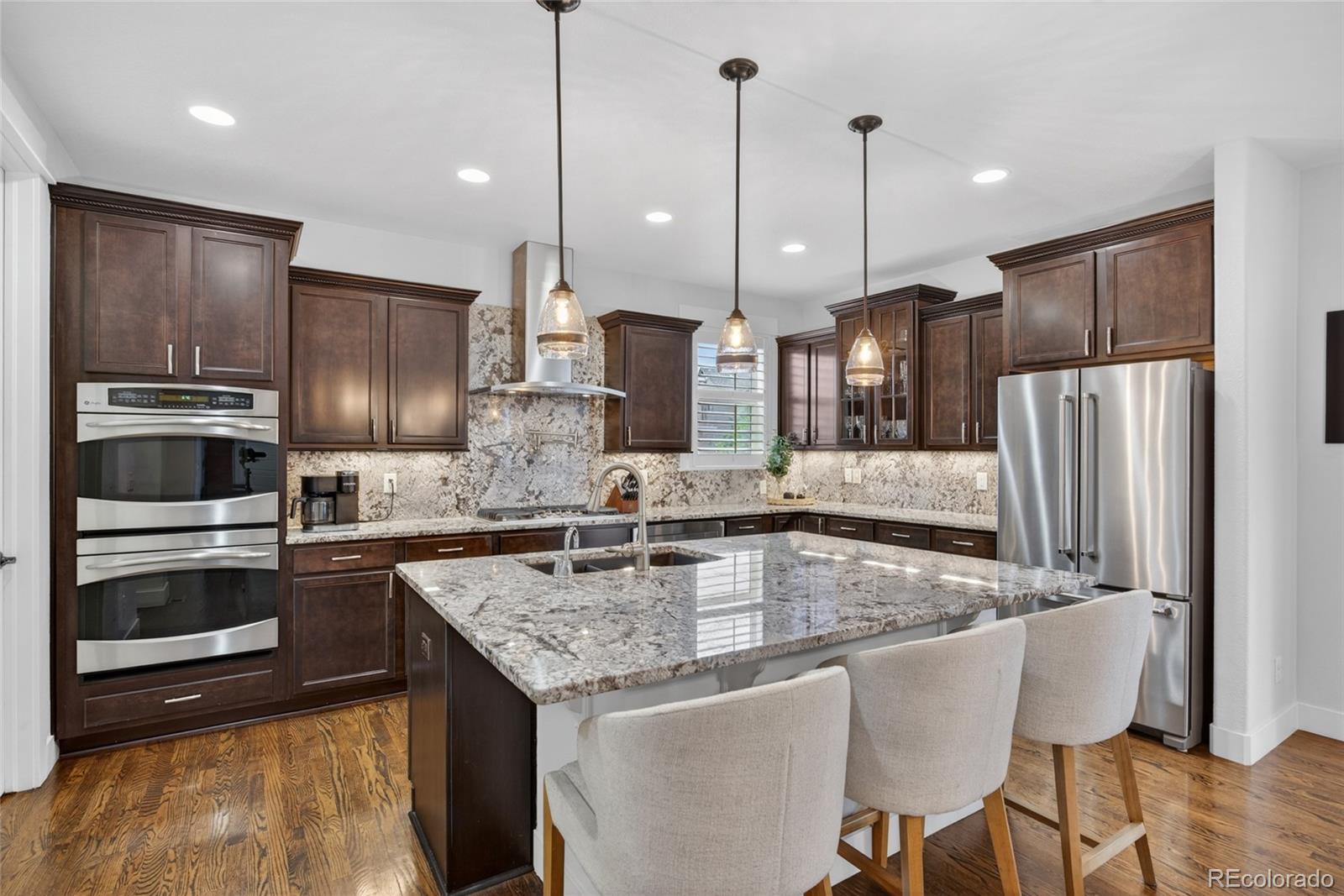 20554 East Shady Ridge Road Parker, CO 80134 - Photo 5 of 49 a kitchen with stainless steel appliances granite countertop a kitchen island hardwood floor sink and stove