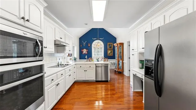 a kitchen with stainless steel appliances granite countertop a refrigerator a stove and a sink