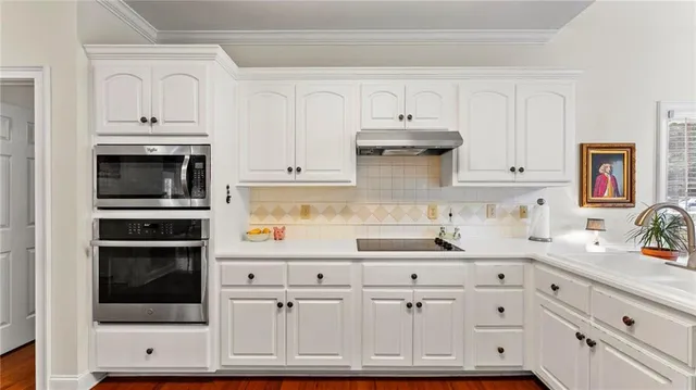 a kitchen with granite countertop white cabinets and stainless steel appliances