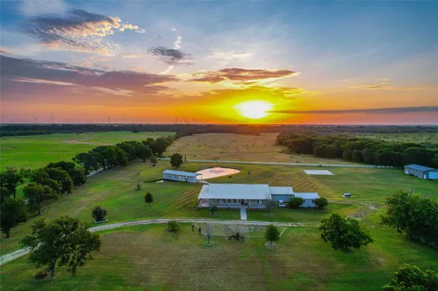 a view of a lake with lawn chairs and large trees