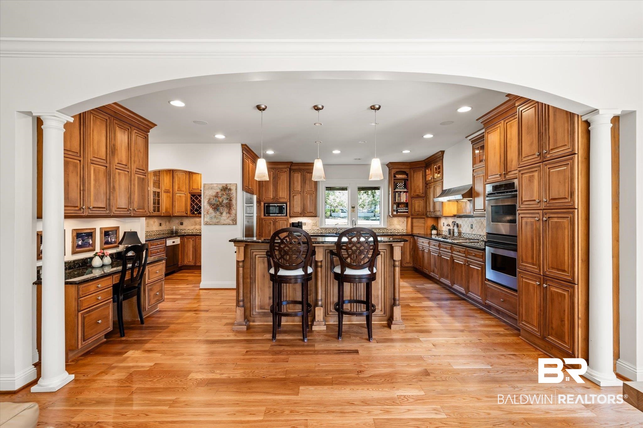 4 Kingsway Mobile, AL 36608 - Photo 11 of 44 Kitchen featuring a center island, a breakfast bar area, brown cabinets, stainless steel appliances, and ornate columns
