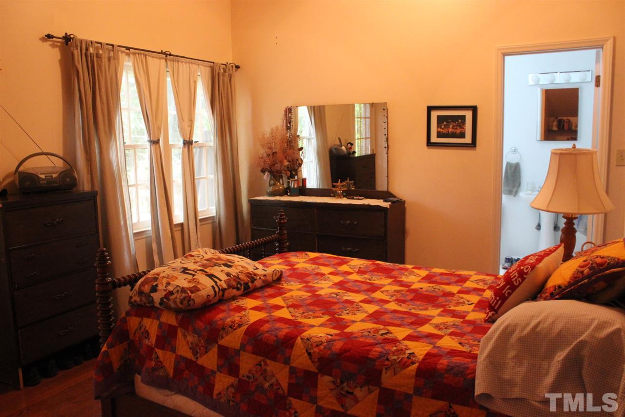 521 Mills Street Raleigh, NC 27608 - Photo 8 of 16 a bedroom with a bed and a lamp on dresser
