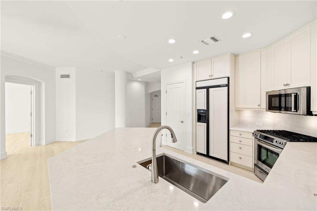 9123 Strada Place, Unit 7316 Naples, FL 34108 - Photo 12 of 47 Kitchen featuring a sink, backsplash, appliances with stainless steel finishes, visible vents, and arched walkways