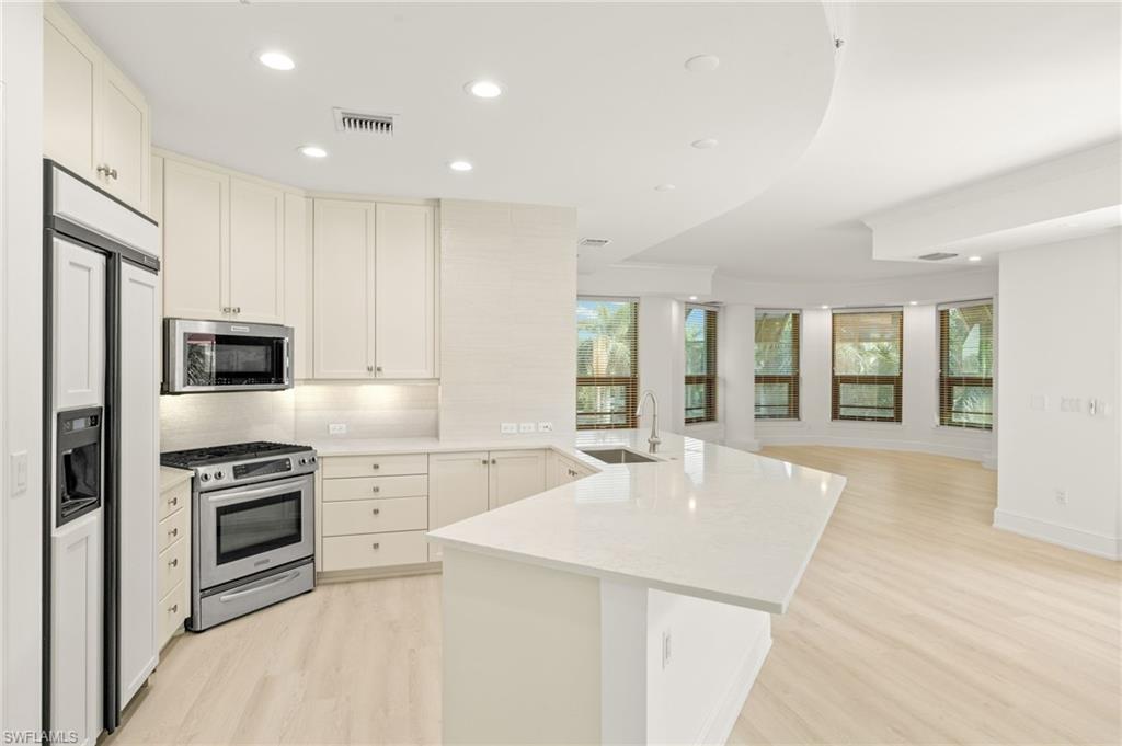 9123 Strada Place, Unit 7316 Naples, FL 34108 - Photo 15 of 47 Kitchen with a sink, light wood finished floors, appliances with stainless steel finishes, a peninsula, and visible vents