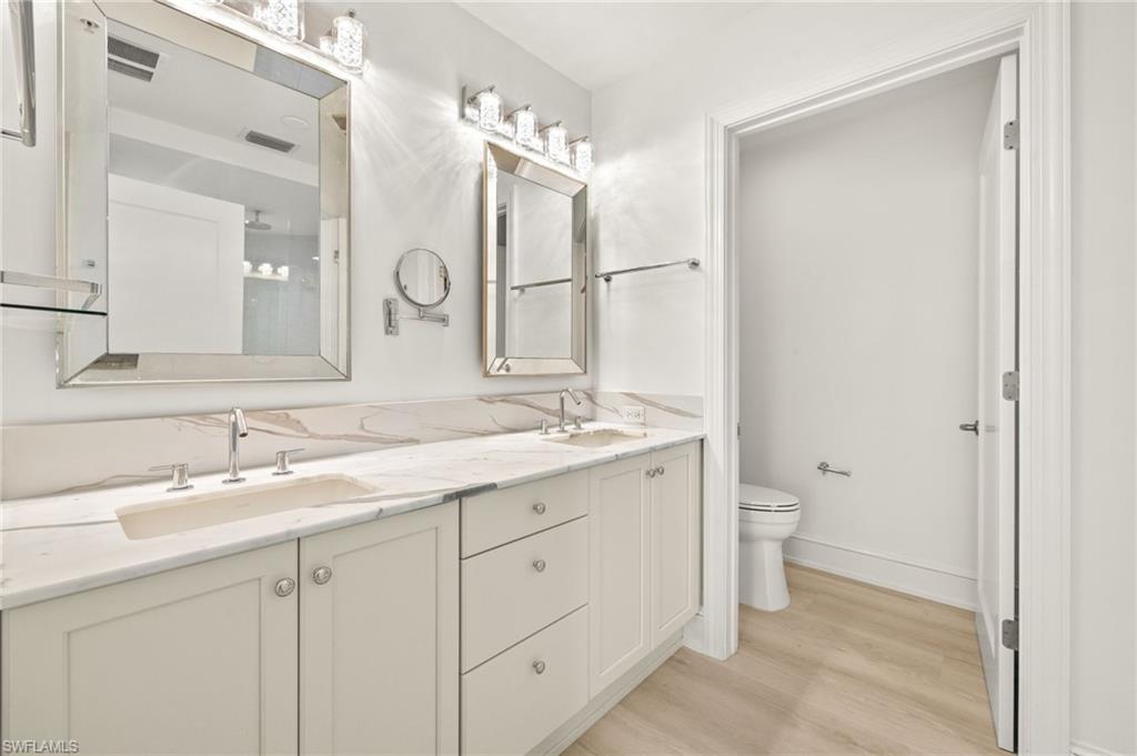 9123 Strada Place, Unit 7316 Naples, FL 34108 - Photo 20 of 47 Bathroom with toilet, a sink, double vanity, and wood finished floors