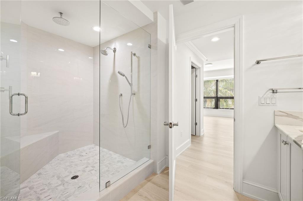 9123 Strada Place, Unit 7316 Naples, FL 34108 - Photo 21 of 47 Bathroom with a shower stall, baseboards, wood finished floors, recessed lighting, and vanity