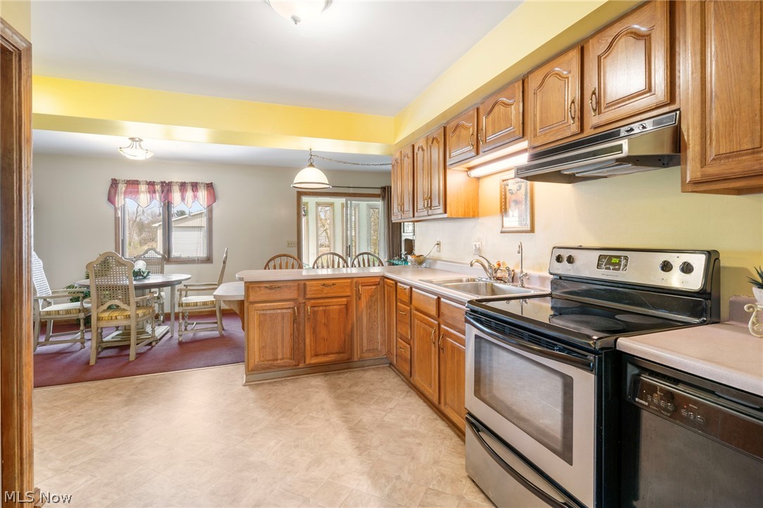 1850 South Sawburg Road Alliance, OH 44601 - Photo 12 of 39 Kitchen with decorative light fixtures, light vinyl floors, kitchen peninsula, dishwasher, and electric range oven