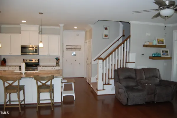 a living room with furniture kitchen view and a wooden floor