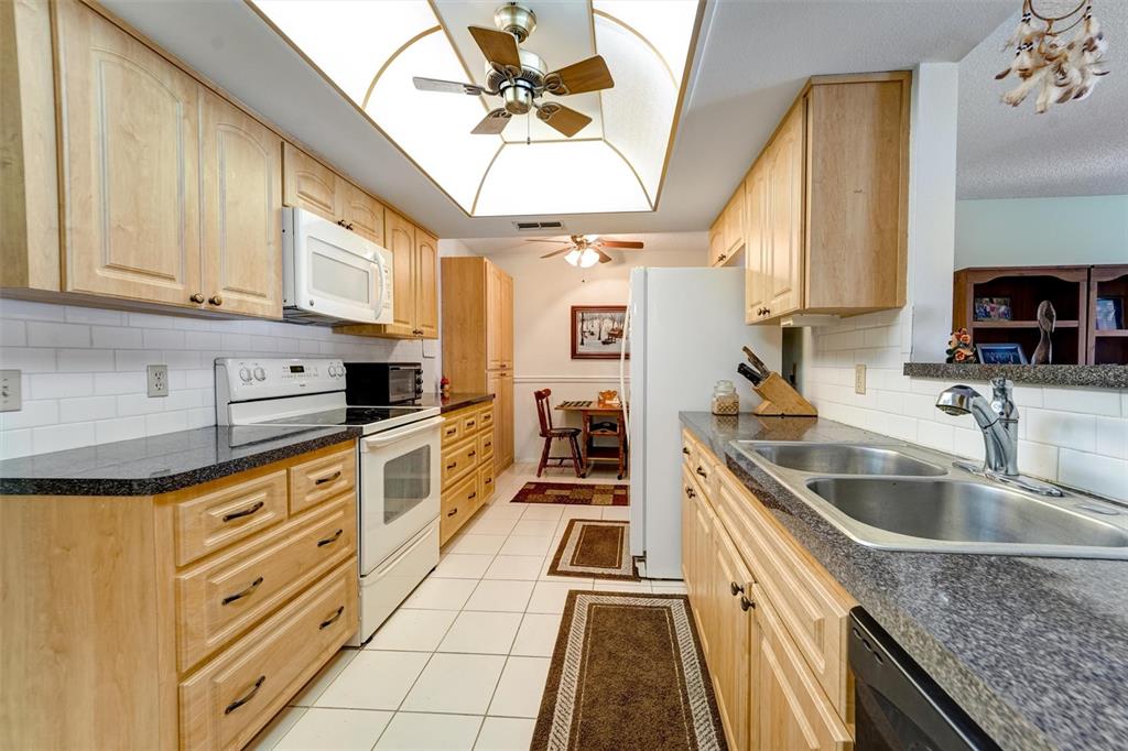 8360 High Point Circle, Unit 3 Port Richey, FL 34668 - Photo 11 of 15 a kitchen with granite countertop a sink a counter top space appliances and cabinets