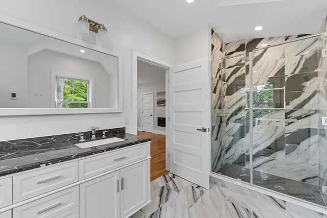 a bathroom with a granite countertop sink a mirror and a shower