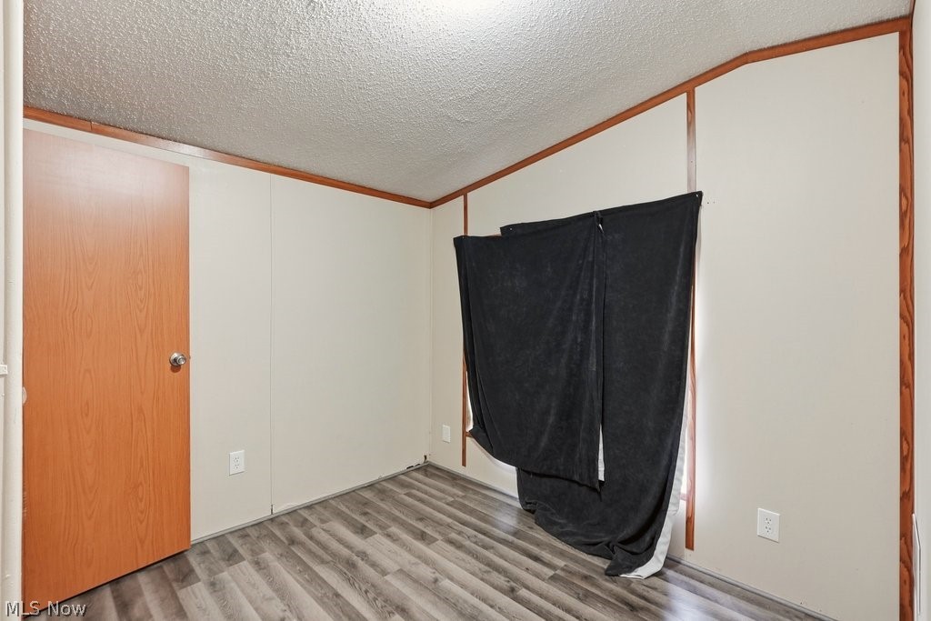6507 Robby Lane Ravenna, OH 44266 - Photo 21 of 25 Unfurnished bedroom featuring a textured ceiling, light wood-style flooring, and crown molding