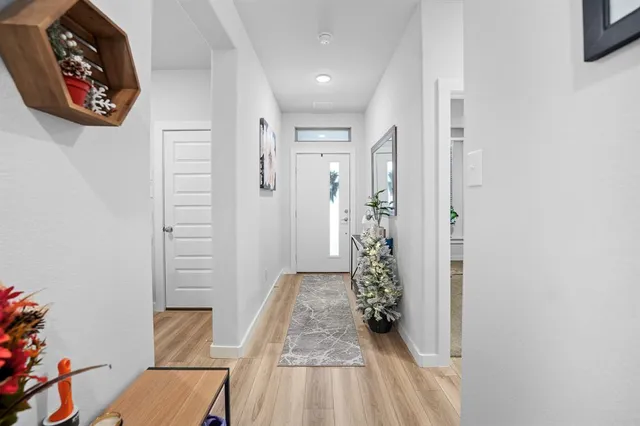 a hallway with a dining table plants and wooden floor