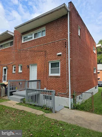 a brick house with a small yard and wooden fence