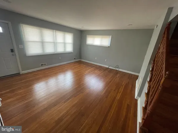 an empty room with wooden floor and staircase