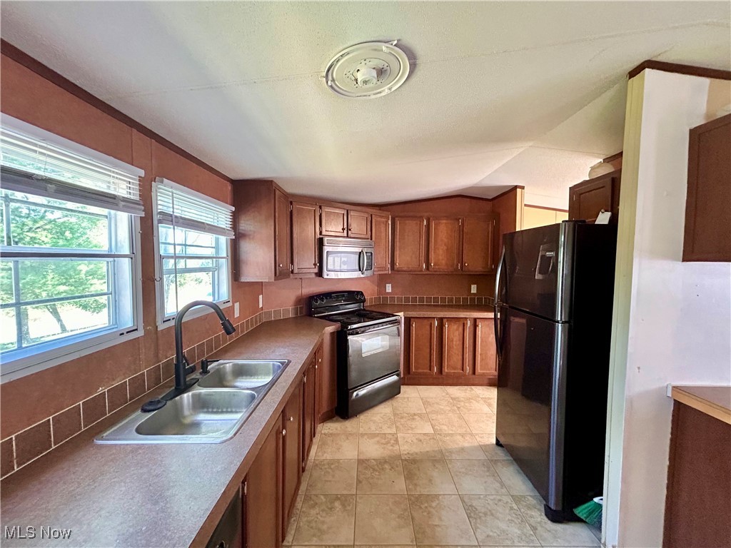 84550 Snyder Road Jewett, OH 43986 - Photo 5 of 21 Kitchen featuring black appliances, decorative backsplash, and brown cabinetry