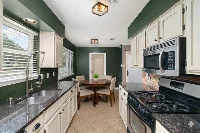 a kitchen with stainless steel appliances granite countertop a stove a sink and a microwave