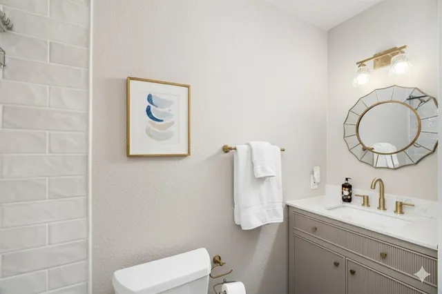a bathroom with a toilet sink vanity and mirror