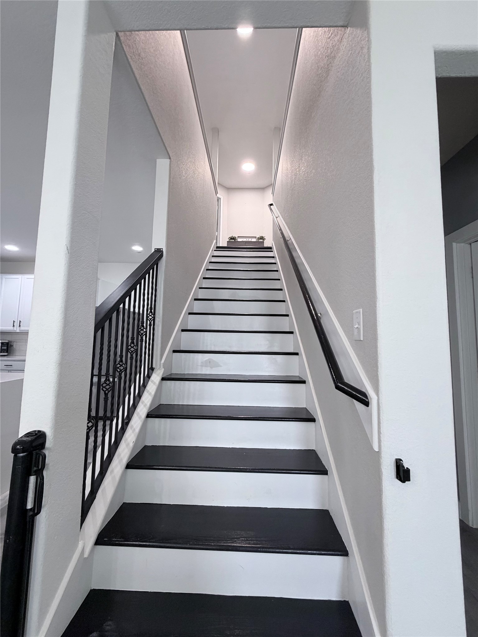 3226 Dappled Vale Trail Spring, TX 77373 - Photo 8 of 26 A modern, well-lit staircase with black steps and white risers. It features sleek black railings and leads to the upper floor, creating a stylish and inviting entrance.