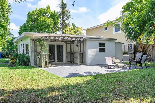 a backyard of a house with table and chairs plants and large tree